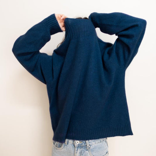 person in navy blue nz charly sweater made from merino and possum, pulling the jumper over their head