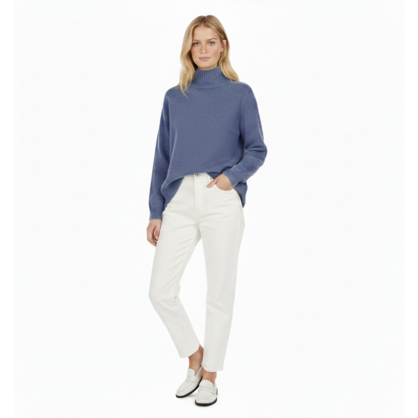 Woman wearing a blue turtleneck sweater and white pants on a white background