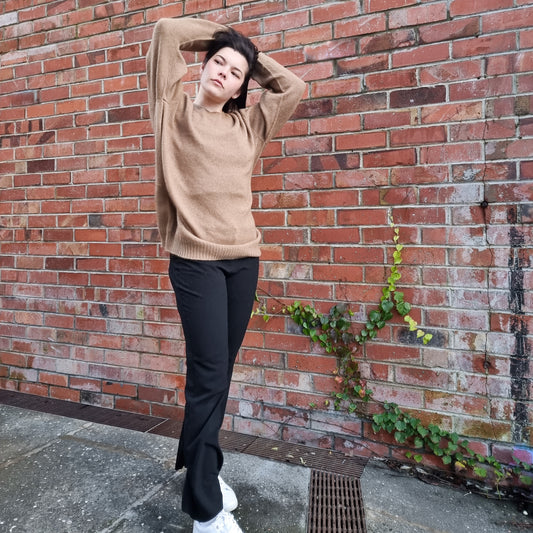 Unisex Mens Jumper. Black haired woman wearing oversize jumper in a caramel brown colour. Sweater made from Merino Possum Angora and Silk. Knitted locally in New Zealand by an Ethical, sustainable female designer. Jumper has a thin rolled crew neck detail and long sleeves