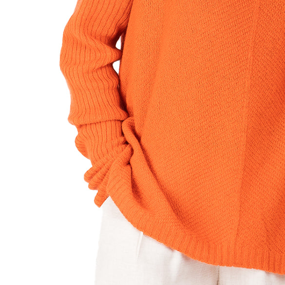 detail view of ribbed hem cashmere possum silk knitted sweater in a bright orange, made in new zealand. Ribbed angled lines on the body of the sweater and long ribbed sleeves