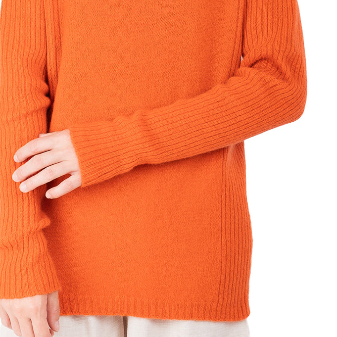 detail view of ribbed hem cashmere possum silk knitted sweater in a bright orange, made in new zealand. Ribbed lines down the sides of the sweater and long ribbed sleeves