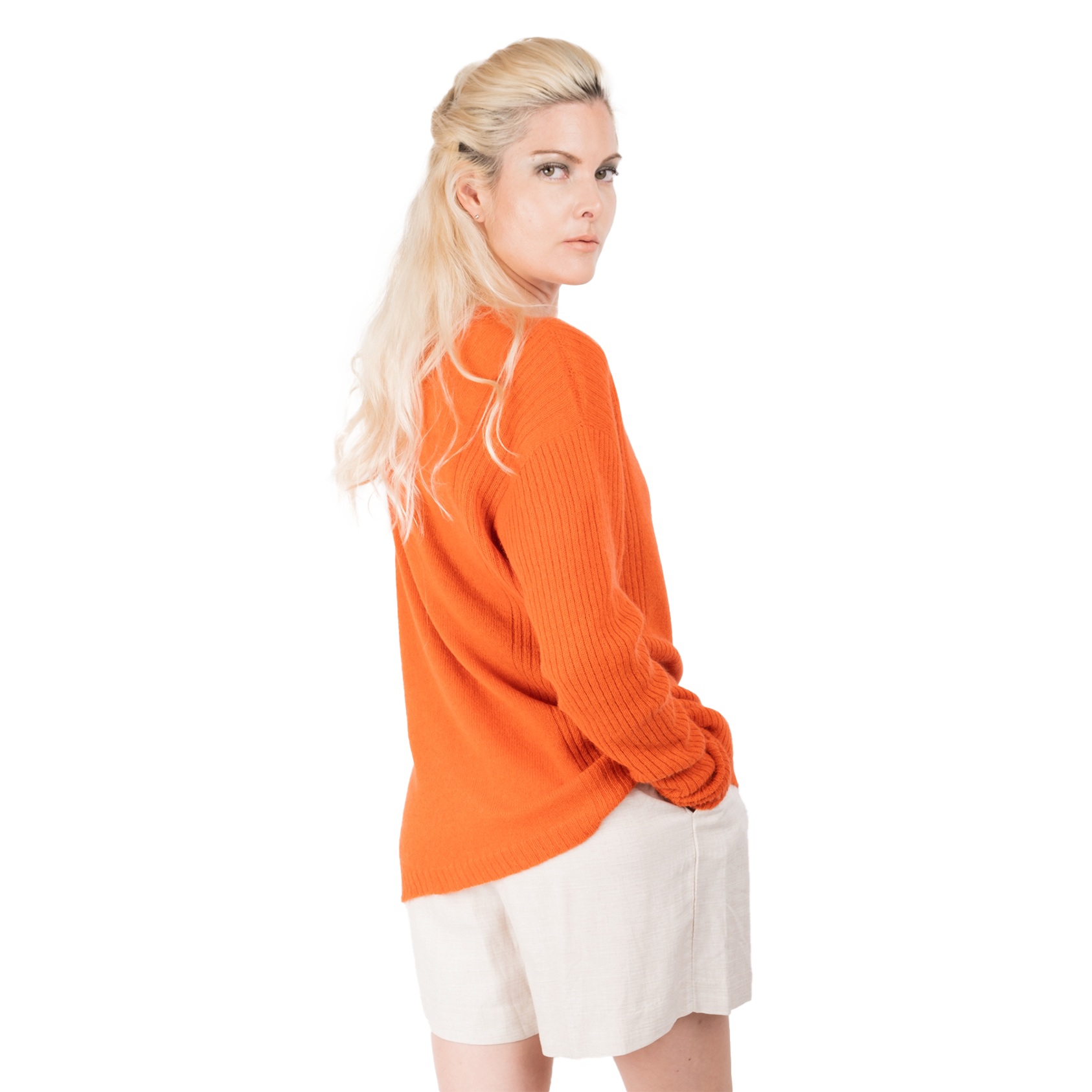 Blonde lady wearing a bright orange cashmere possum silk sweater. It has long ribbed sleeves and rib stripes down the sides of the body. Made in New zealand. She is facing the back looking backwards over her shoulder
