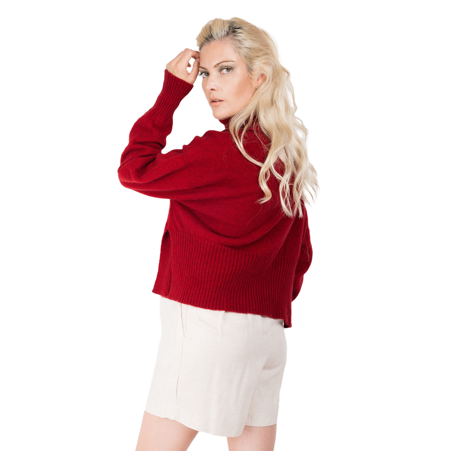 Blond lady wearing a bright red jumper. Cropped body with a long split ribbed hem. Turtleneck and ribbed cuffs. Sweater made from Merino possum and nylon and made in new zealand