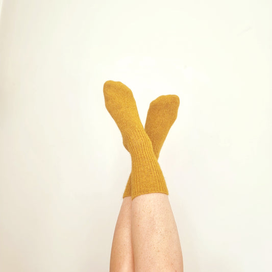 Sunflower yellow merino possum blend socks on feet sticking up into the air