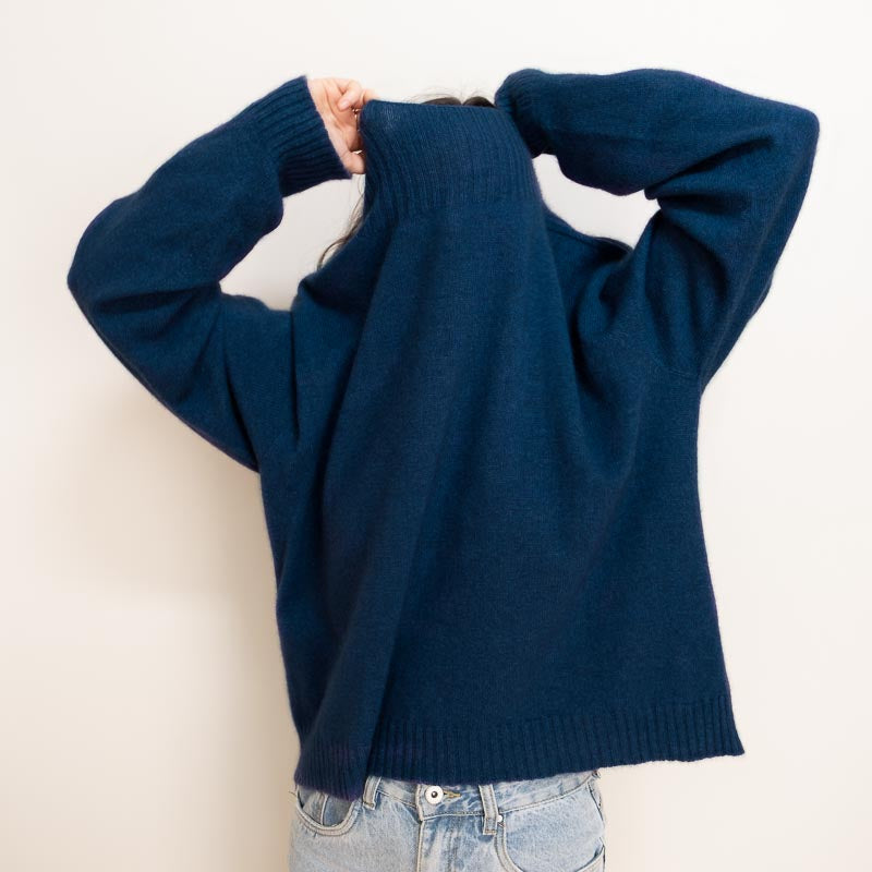 person in navy blue nz charly sweater made from merino and possum, pulling the jumper over their head