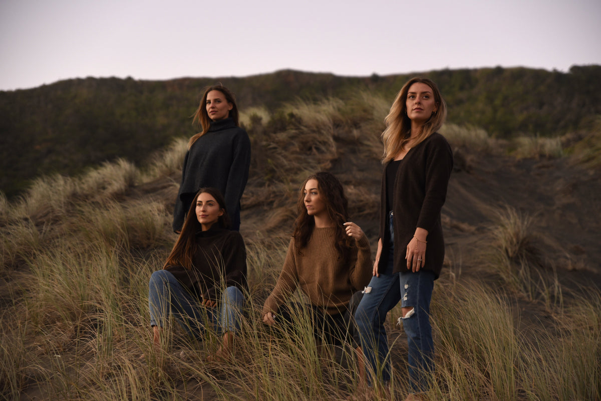 Four women standing in a grassy field with a blurred background
