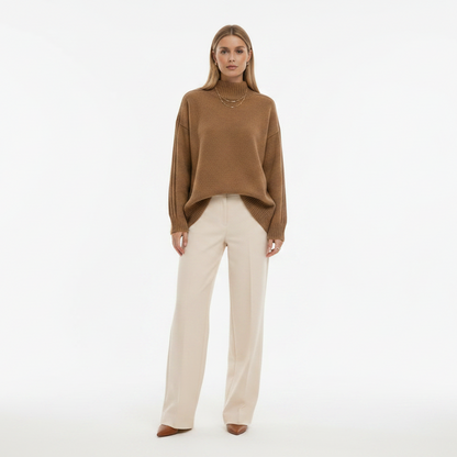 Woman wearing a brown sweater and beige pants on a white background