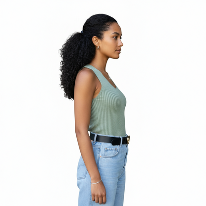 Woman wearing a light green sleeveless top and blue jeans on a white background