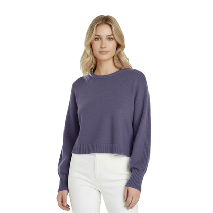 Woman wearing a smoke gray / purple sweater and white pants on a white background
