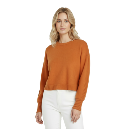 Woman wearing an orange sweater and white pants on a white background