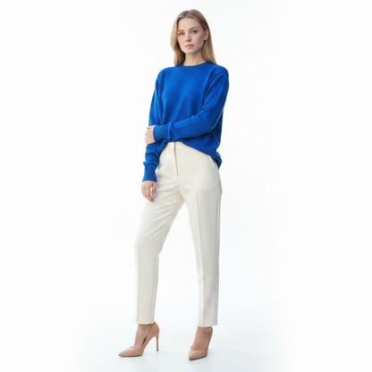 Woman wearing a blue sweater and white pants on a white background