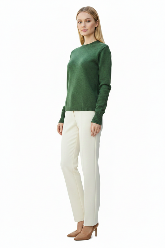 Woman wearing a green sweater and white pants on a white background