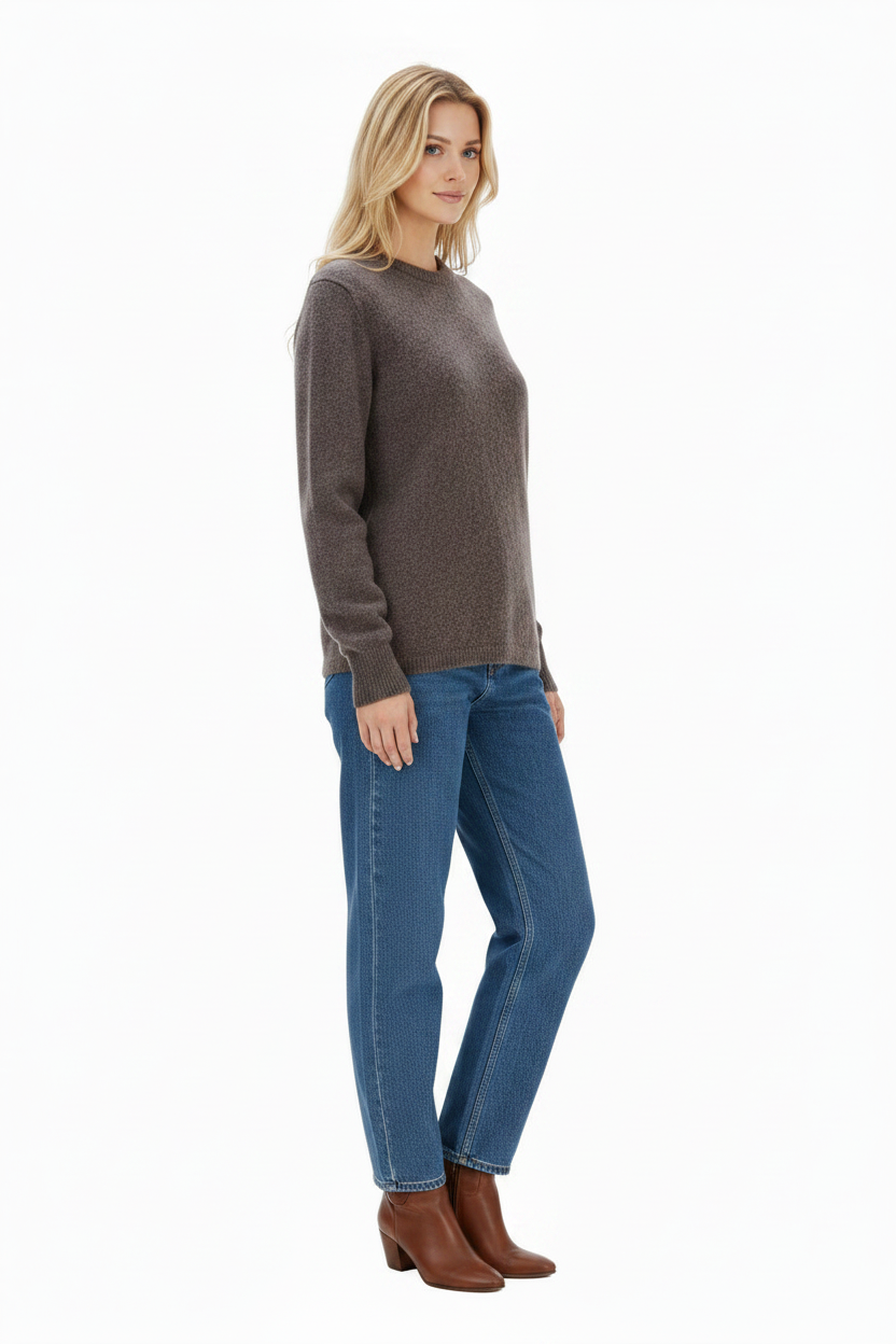 Woman wearing a brown sweater and blue jeans on a white background