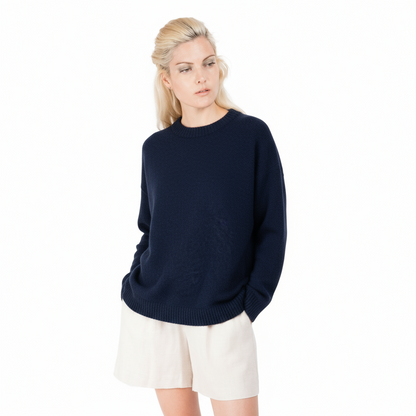 Blond lady wearing a deep inky blue knitted jumper. Sweater made from Merino possum and nylon and made in new zealand. She is facing the front with her arm relaxed down by her side showing off the ribbed line detail on the top of the sleeves of the sweater