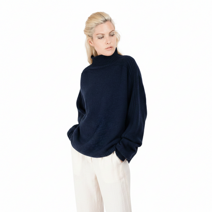 Woman wearing a navy blue sweater and white pants on a white background