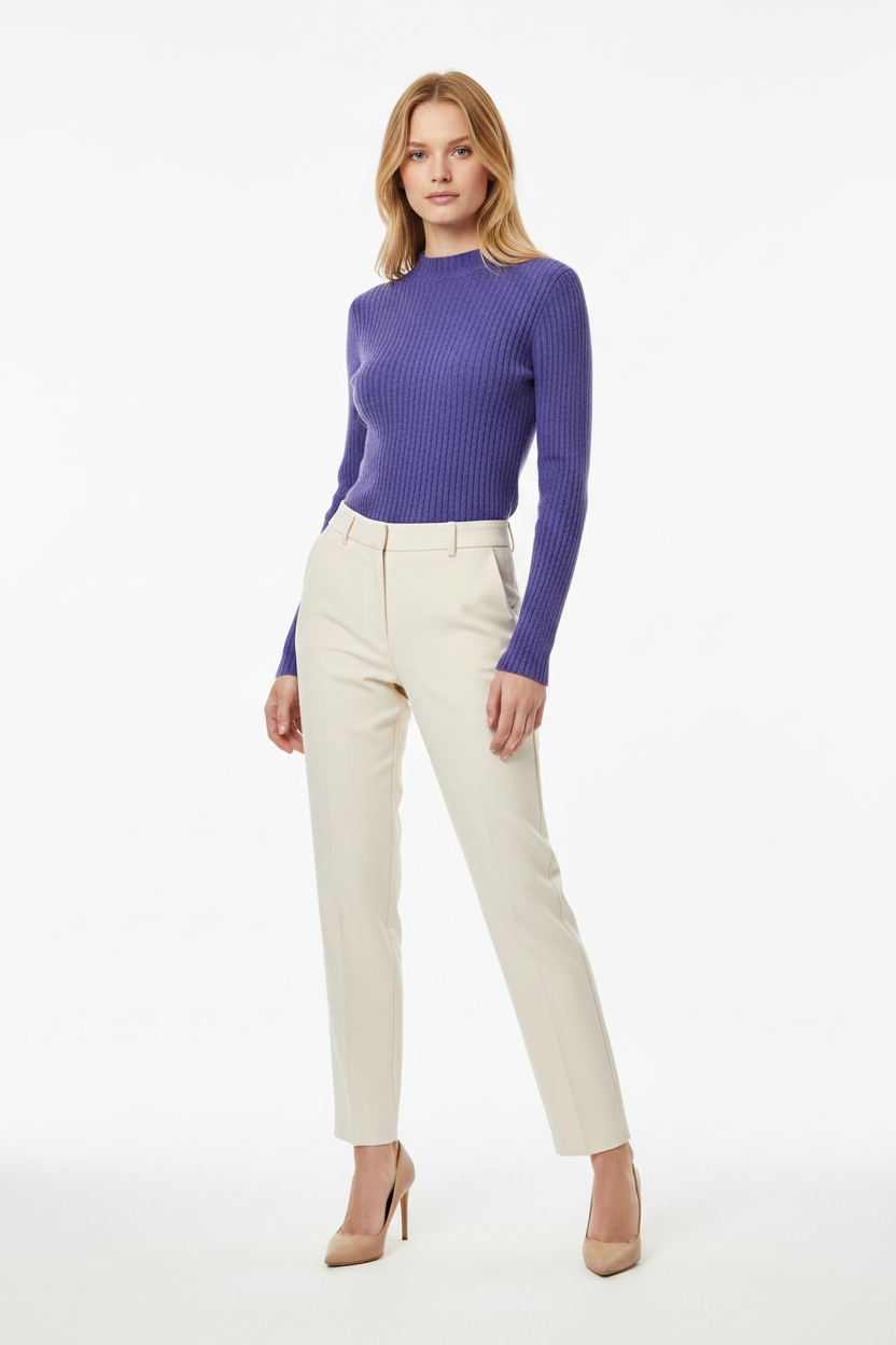 Woman wearing a purple ribbed sweater and beige pants on a white background