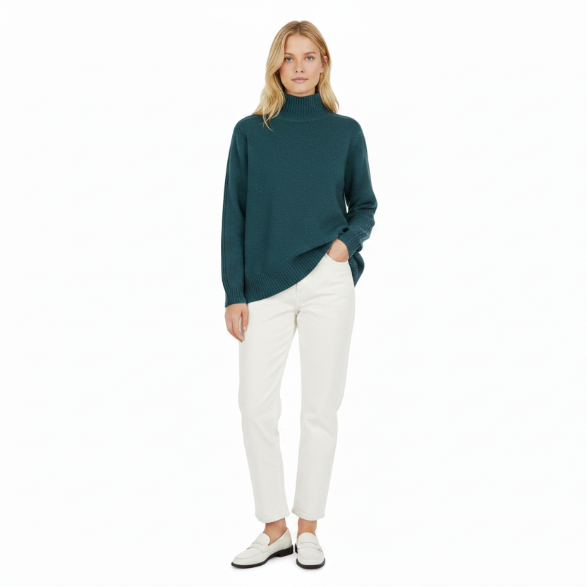 Woman wearing a teal sweater and white pants on a white background