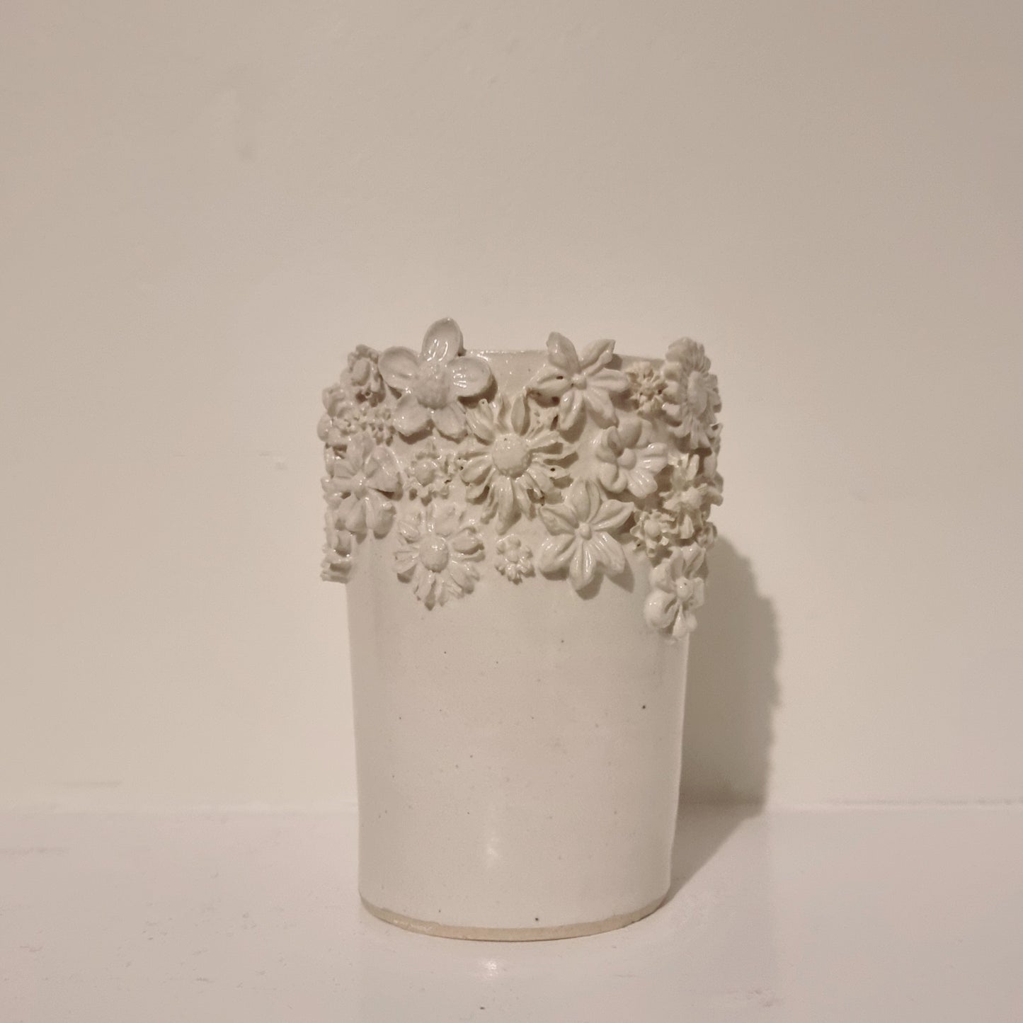 Medium straight vase with flowers around the top. White ceramic