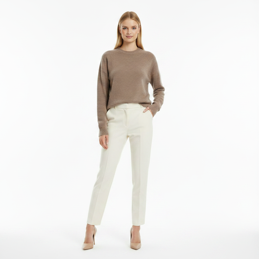 Woman wearing a brown sweater and white pants on a white background