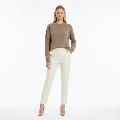 Woman wearing a brown sweater and white pants on a white background
