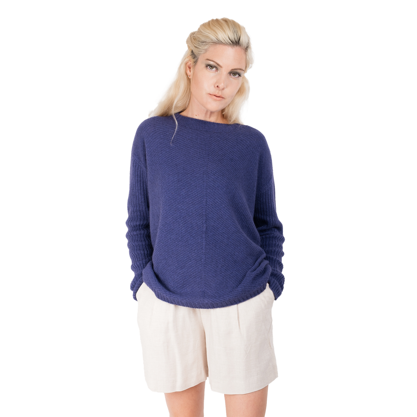 Blonde lady wearing a purple cashmere possum silk sweater. It has long ribbed sleeves and rib angled detail knitted on the body. Made in New zealand. 