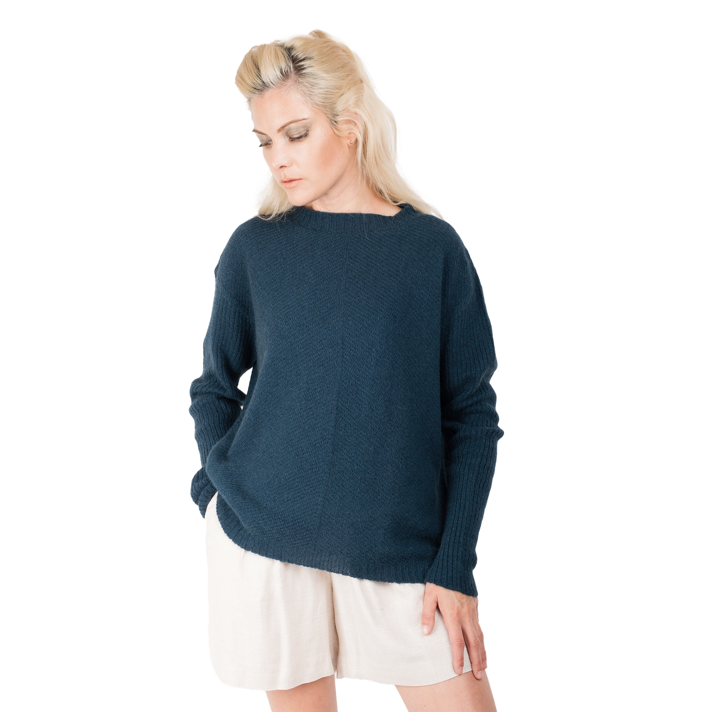 Blonde lady wearing a ocean teal blue cashmere possum silk sweater. It has long ribbed sleeves and rib angled detail knitted on the body. Made in New zealand. 