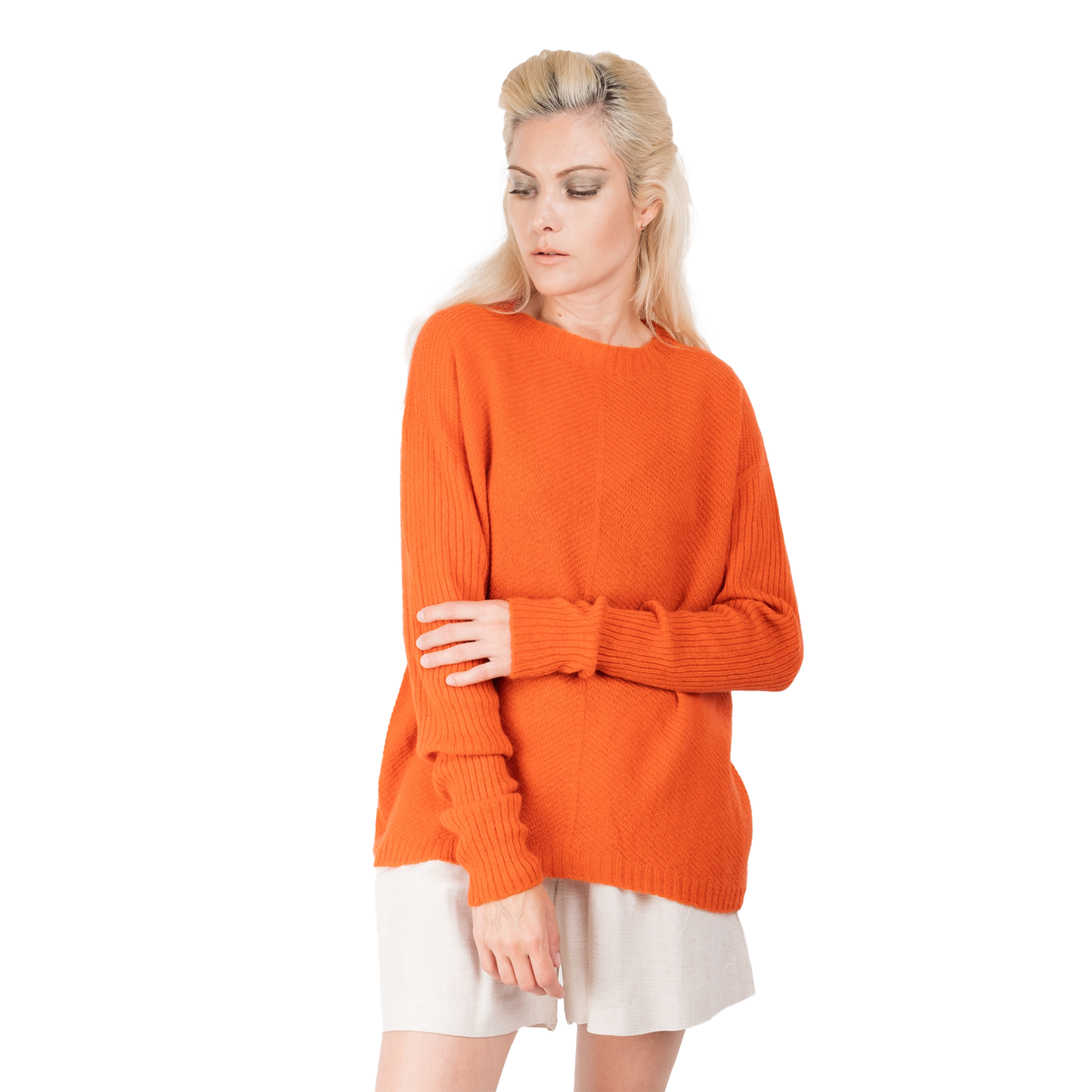 Blonde lady wearing a bright orange cashmere possum silk sweater. It has long ribbed sleeves and rib angled detail knitted on the body. Made in New zealand. 
